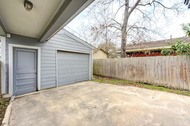 garage featuring fence and concrete driveway