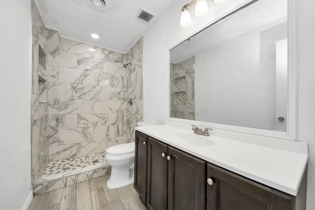 bathroom featuring tiled shower, vanity, and toilet