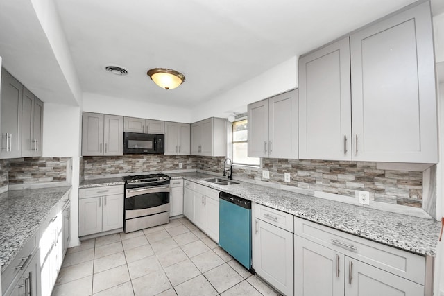 kitchen with sink, appliances with stainless steel finishes, gray cabinetry, light tile patterned flooring, and decorative backsplash