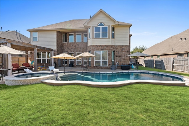 rear view of property featuring a swimming pool with hot tub, a lawn, and a patio