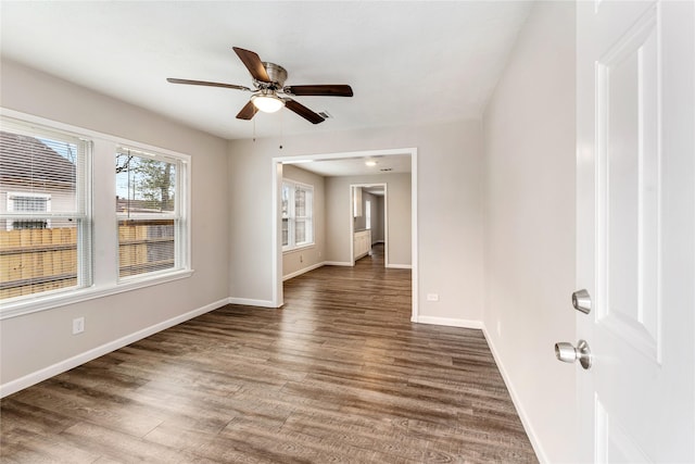 unfurnished room with a ceiling fan, baseboards, and wood finished floors