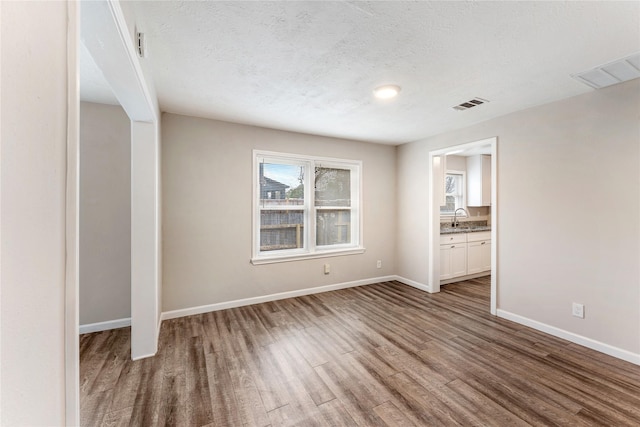 3722 Seabrook St, Houston, TX 77021 - empty room featuring a sink, wood finished floors, baseboards, and a textured ceiling