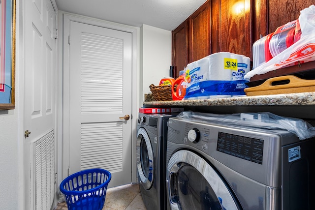 clothes washing area with cabinets, light tile patterned floors, washer and dryer, and a textured ceiling