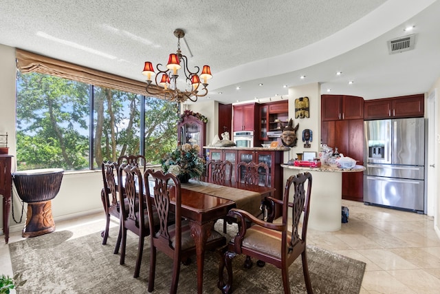 tiled dining room with a notable chandelier and a textured ceiling