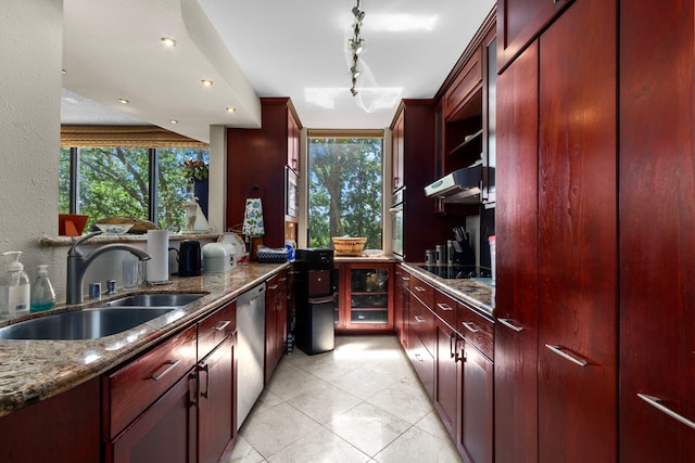 kitchen featuring rail lighting, sink, stone countertops, light tile patterned floors, and appliances with stainless steel finishes