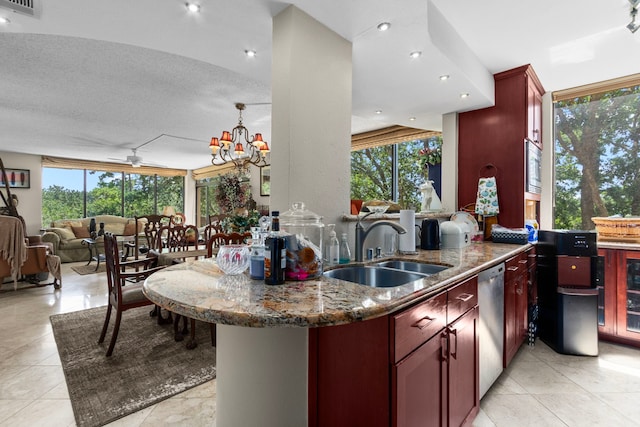 kitchen featuring sink, a wealth of natural light, kitchen peninsula, a textured ceiling, and dark stone counters