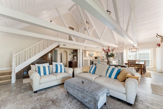 living room featuring beamed ceiling, a notable chandelier, and high vaulted ceiling