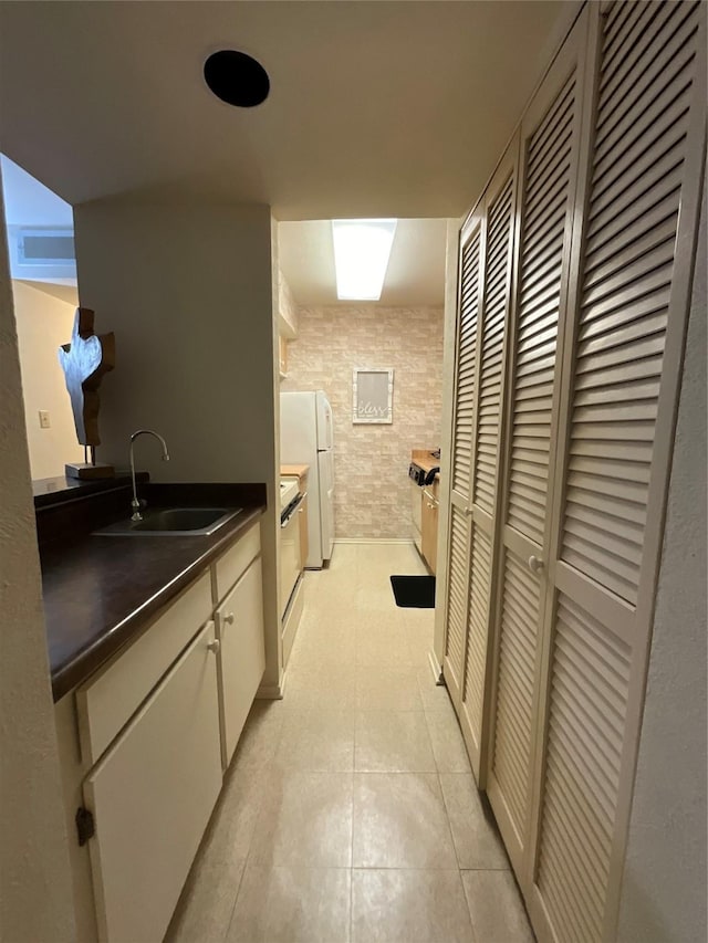 kitchen with light tile patterned flooring, sink, and white fridge