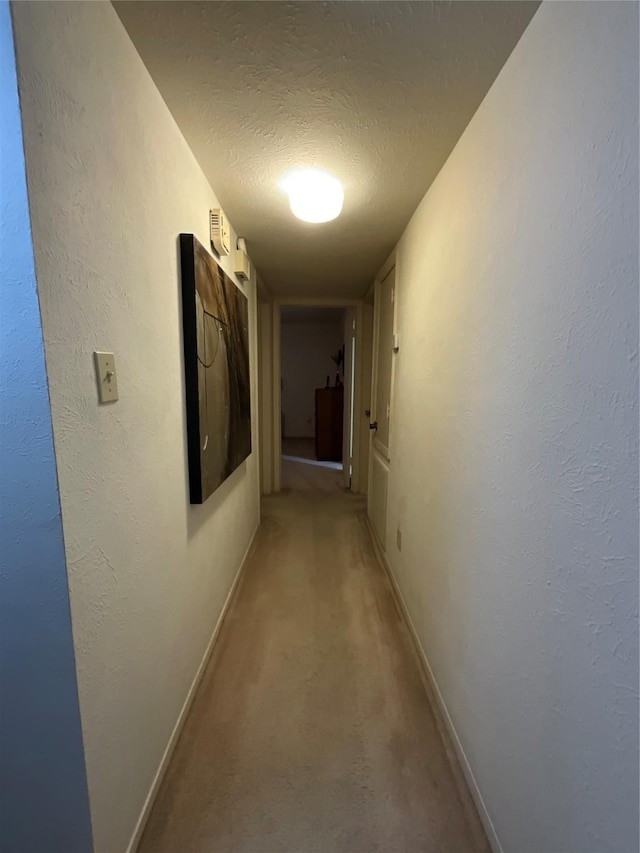 hall featuring a textured ceiling and carpet flooring