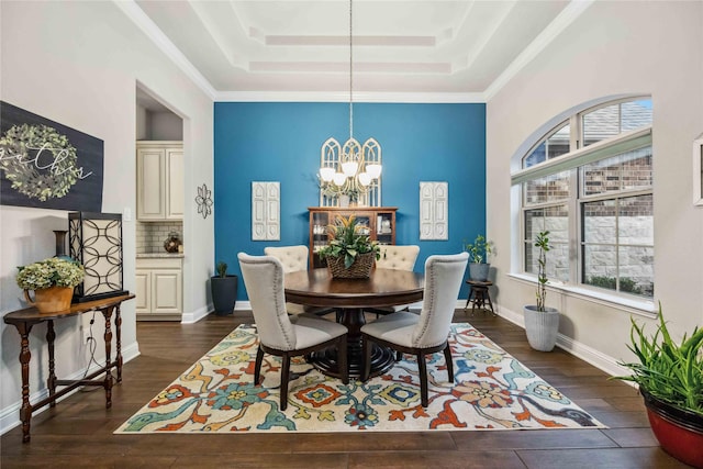 dining area with ornamental molding, dark hardwood / wood-style floors, a chandelier, and a tray ceiling