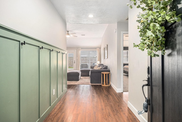 corridor with dark hardwood / wood-style flooring and a textured ceiling