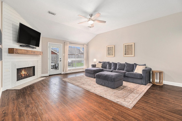 living room featuring lofted ceiling, dark wood-type flooring, a large fireplace, and ceiling fan