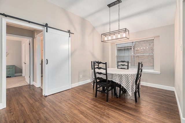 dining area with a barn door, dark hardwood / wood-style flooring, and vaulted ceiling