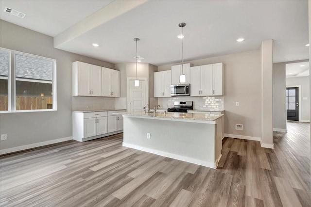 kitchen with light stone counters, tasteful backsplash, hanging light fixtures, appliances with stainless steel finishes, and white cabinets