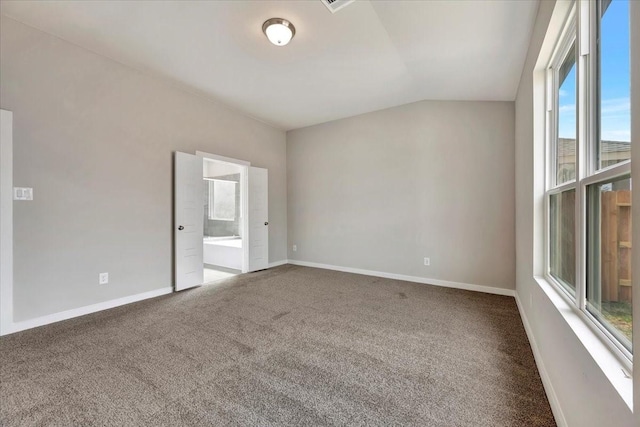 carpeted spare room featuring vaulted ceiling