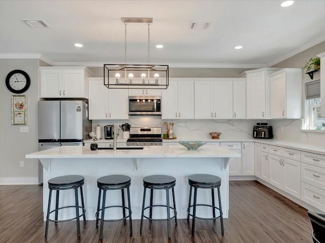 kitchen with a kitchen island with sink, stainless steel appliances, and white cabinets