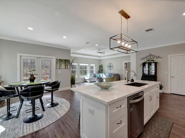 kitchen featuring pendant lighting, sink, dishwasher, white cabinetry, and a kitchen island with sink