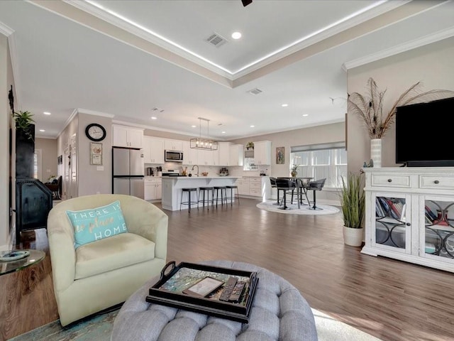 living room featuring ornamental molding, wood-type flooring, and a notable chandelier