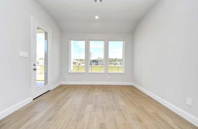 unfurnished room with vaulted ceiling, a healthy amount of sunlight, and light wood-type flooring