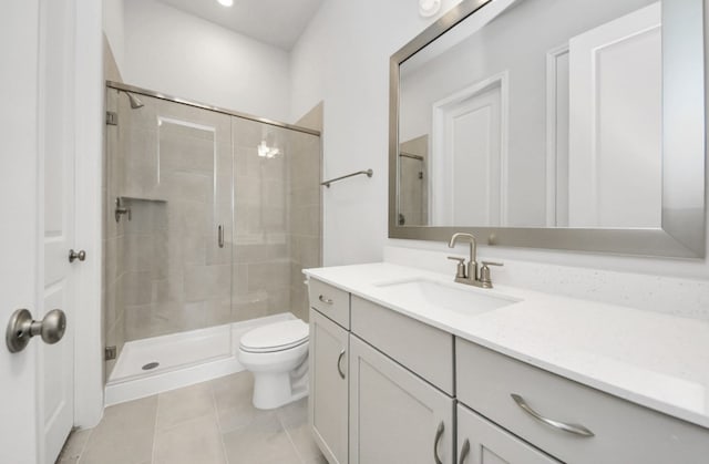 bathroom with tile patterned floors, vanity, toilet, and a shower with shower door