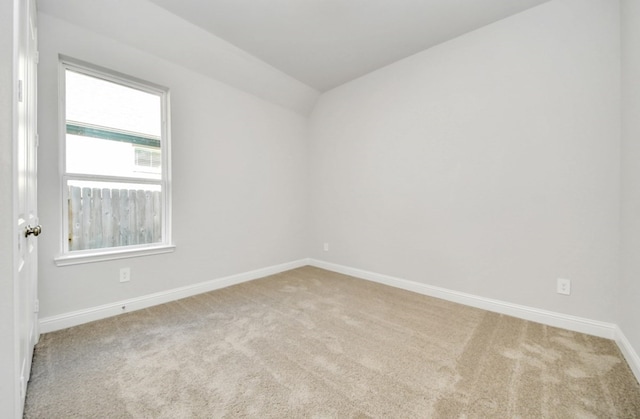 unfurnished room featuring light carpet and vaulted ceiling