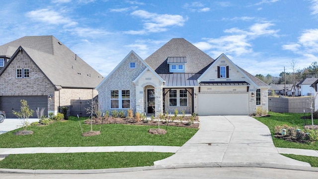 french country home with a garage, fence, concrete driveway, a standing seam roof, and a front yard