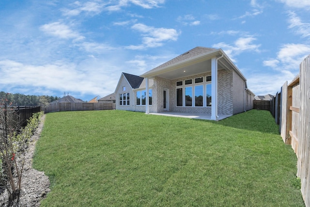 back of house with brick siding, a lawn, a fenced backyard, and a patio