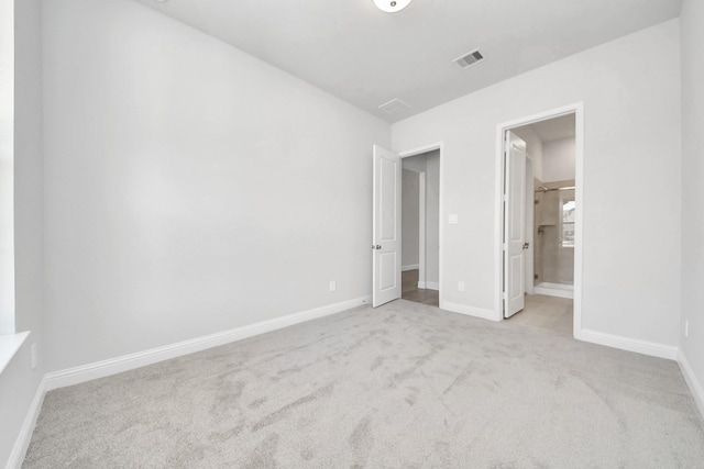 unfurnished bedroom featuring ensuite bath, carpet flooring, visible vents, and baseboards