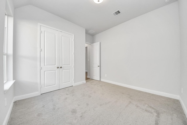 unfurnished bedroom with a closet, carpet flooring, visible vents, and baseboards