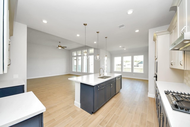 kitchen featuring stainless steel appliances, open floor plan, light wood finished floors, and an island with sink