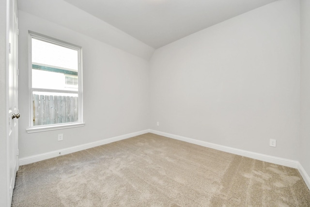 carpeted spare room with baseboards and vaulted ceiling