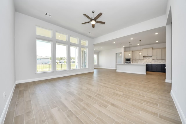 unfurnished living room featuring baseboards, visible vents, ceiling fan, and light wood finished floors