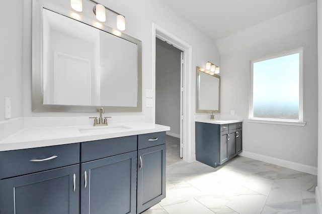 bathroom with marble finish floor, two vanities, a sink, and baseboards