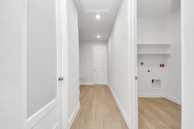 hall with attic access, light wood-type flooring, and baseboards