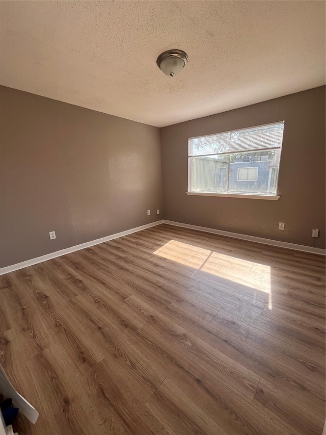 spare room featuring dark wood-type flooring and a textured ceiling