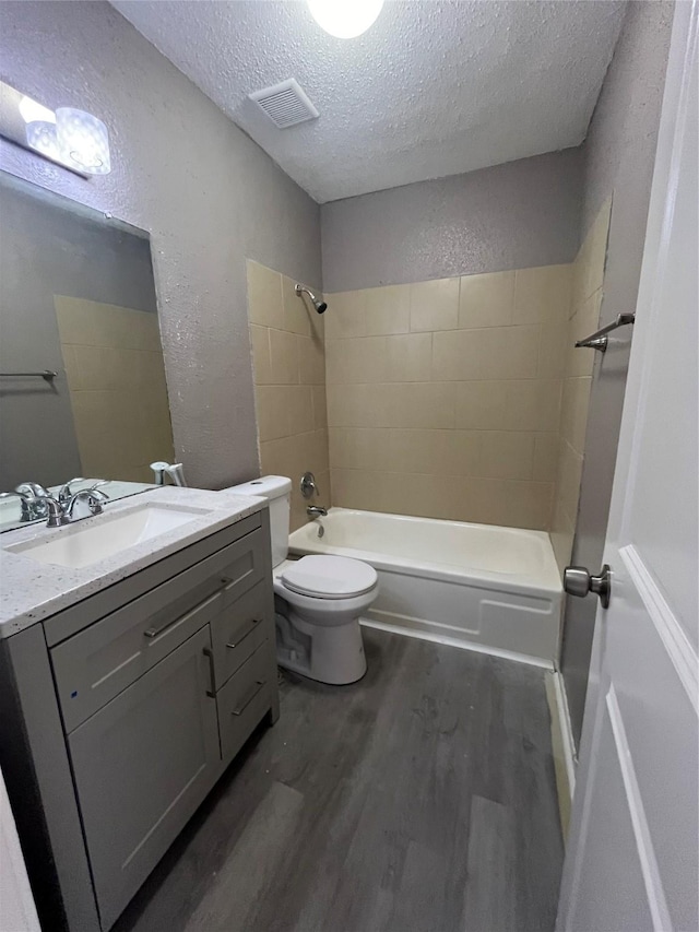 full bathroom featuring toilet,  shower combination, a textured ceiling, vanity, and hardwood / wood-style flooring