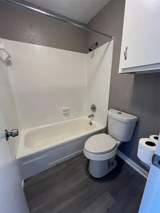 bathroom featuring wood-type flooring, toilet, tub / shower combination, and a textured ceiling