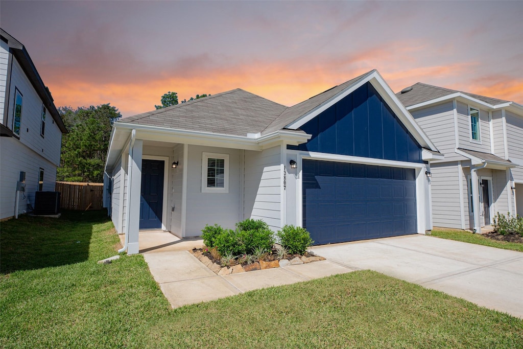 view of front of home featuring cooling unit, a garage, and a yard