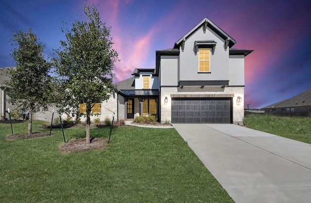 view of front of property featuring an attached garage, concrete driveway, a yard, stucco siding, and a standing seam roof