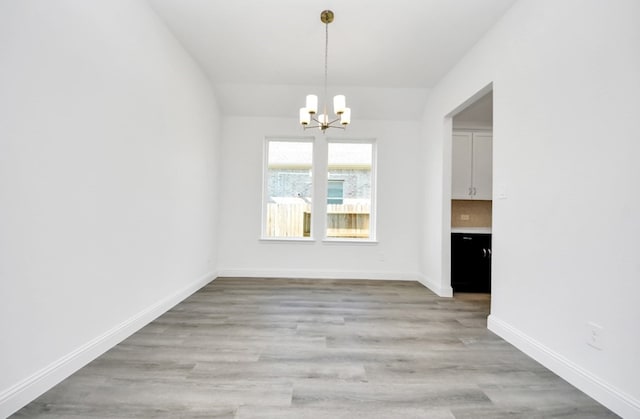 unfurnished dining area with light wood-type flooring and an inviting chandelier