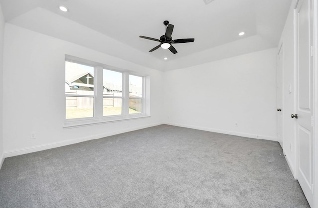 carpeted spare room with ceiling fan and a raised ceiling