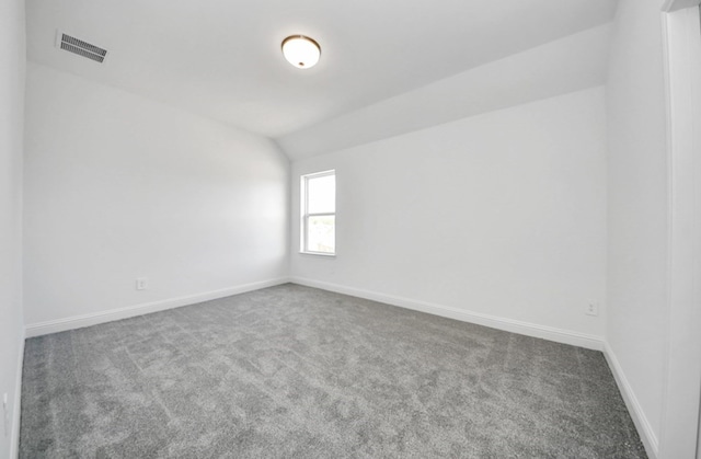 spare room featuring lofted ceiling, carpet flooring, visible vents, and baseboards