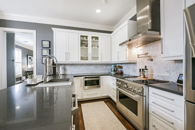 kitchen with crown molding, appliances with stainless steel finishes, white cabinetry, a sink, and wall chimney exhaust hood