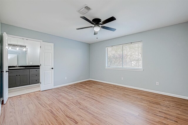 unfurnished bedroom featuring sink, light hardwood / wood-style floors, ceiling fan, and ensuite bathroom