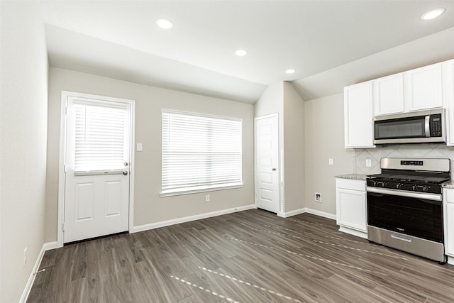 kitchen featuring white cabinetry, vaulted ceiling, dark hardwood / wood-style flooring, stainless steel appliances, and backsplash