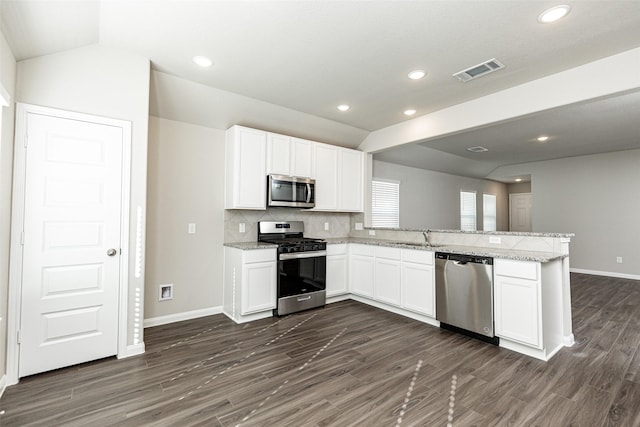 kitchen featuring white cabinetry, light stone counters, appliances with stainless steel finishes, kitchen peninsula, and decorative backsplash