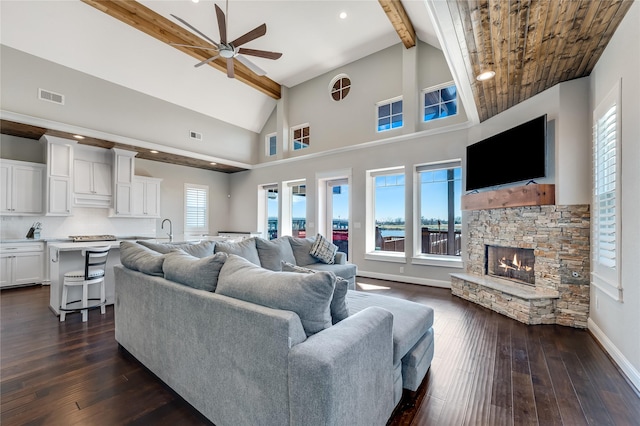 living room featuring dark hardwood / wood-style floors, high vaulted ceiling, a fireplace, ceiling fan, and beam ceiling