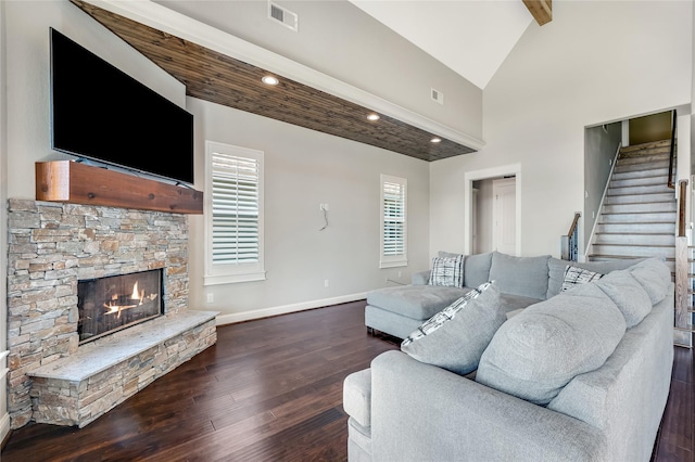 living room featuring vaulted ceiling with beams, dark wood-type flooring, and a fireplace