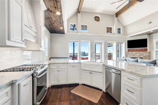 kitchen with appliances with stainless steel finishes, beamed ceiling, white cabinetry, sink, and kitchen peninsula