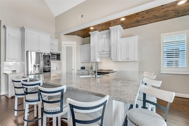 kitchen featuring decorative backsplash, stainless steel fridge, a breakfast bar, and white cabinets